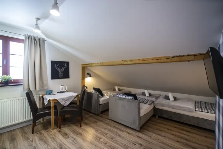 Pokój ze skosami, stolikiem i dwoma łóżkami